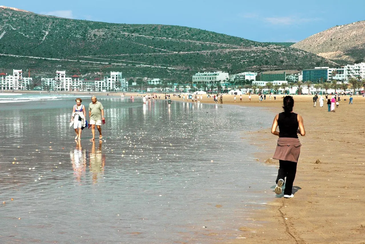 Personas paseando junto a la playa y la bahía de Agadir