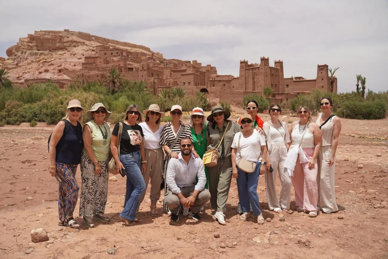 Travelers and their guide posing in front of Ait Ben Haddou