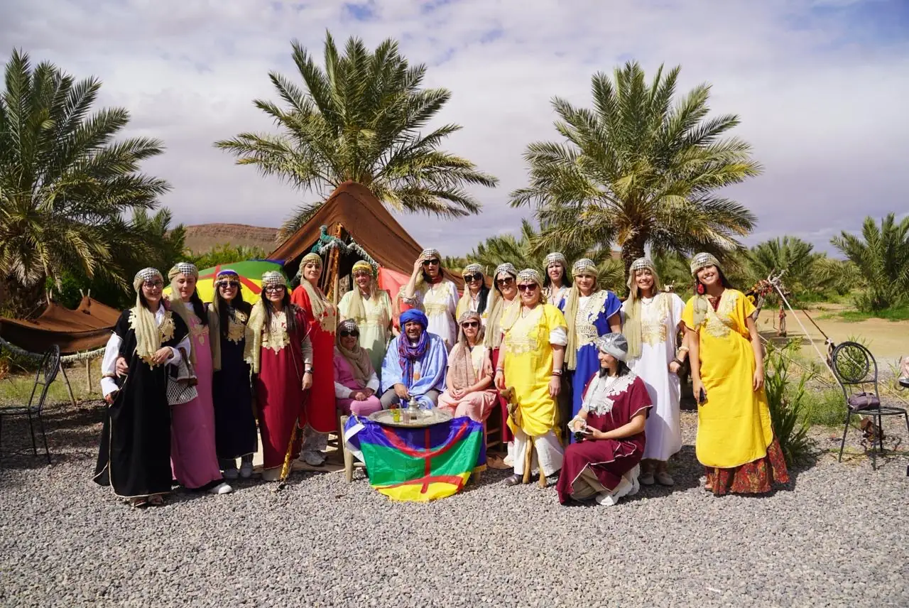 Our travelers in traditional Amazigh dress beside a palm grove and tent