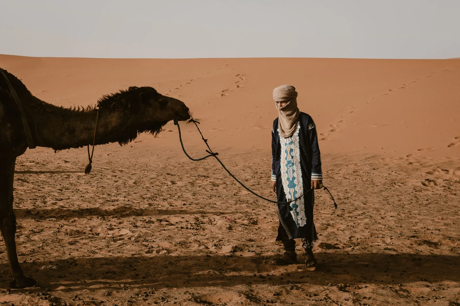 Guía de camellos y un camello al borde de las dunas de Merzouga