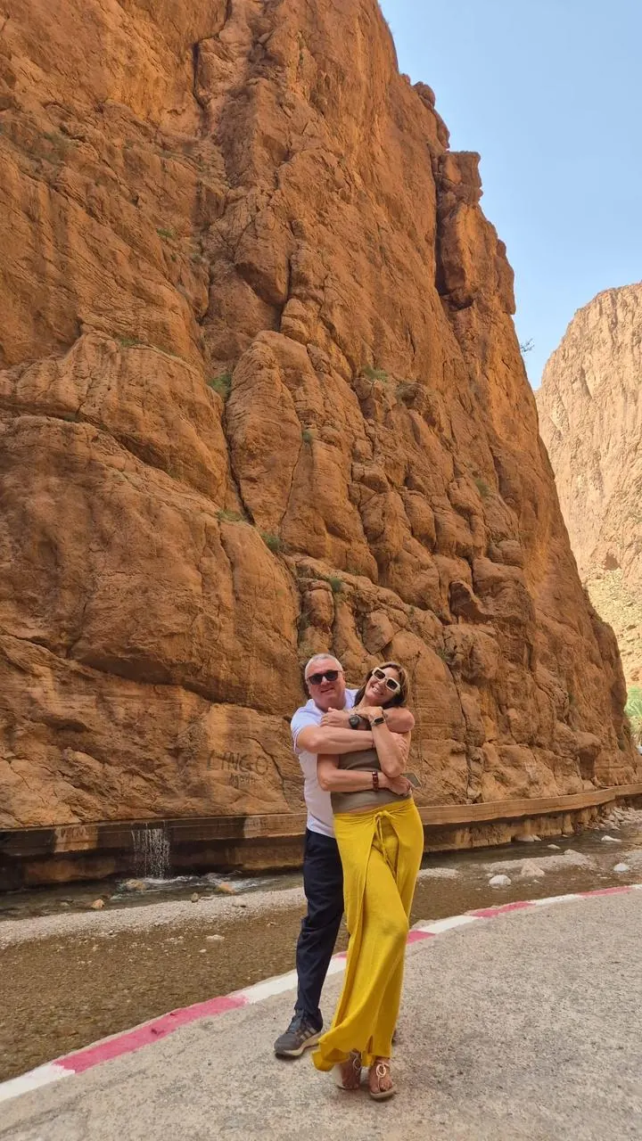 Couple posing beside the river beneath the cliffs of Todra Gorge
