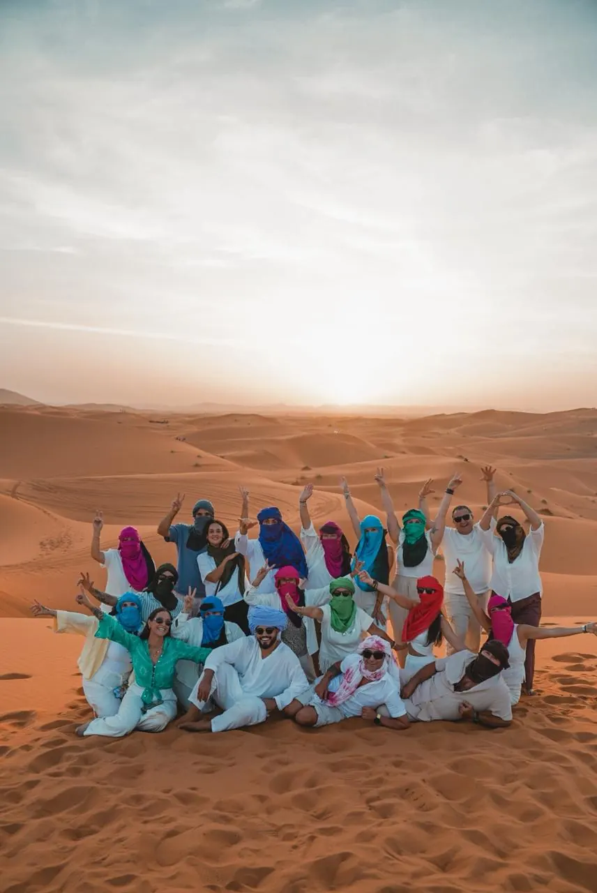 Travelers wearing desert scarves at Erg Chebbi near sunset