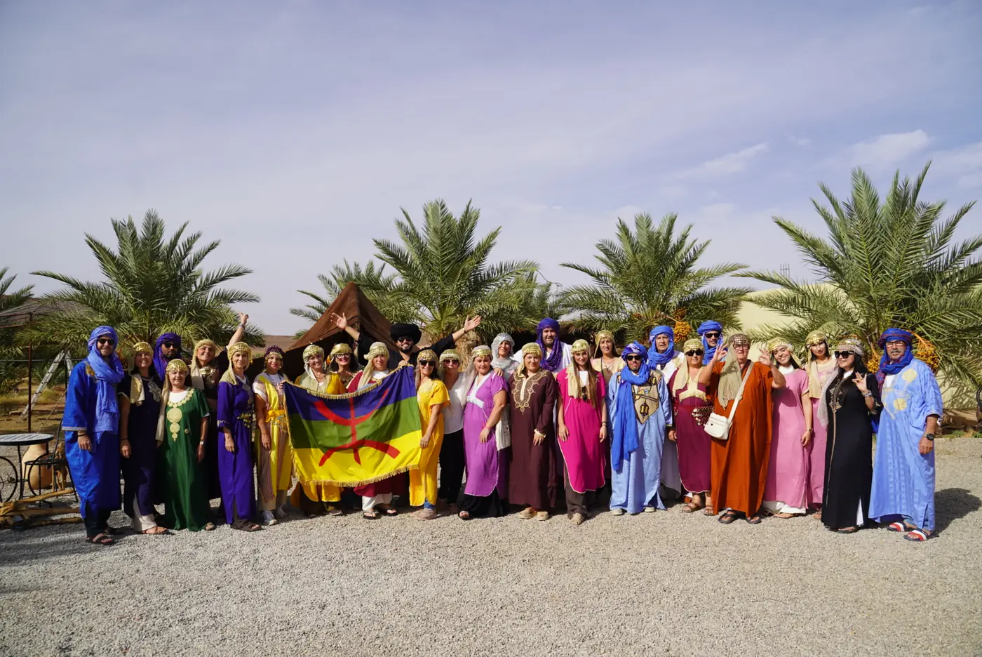 Viajeros con vestimenta tradicional amazigh junto a una tienda del desierto