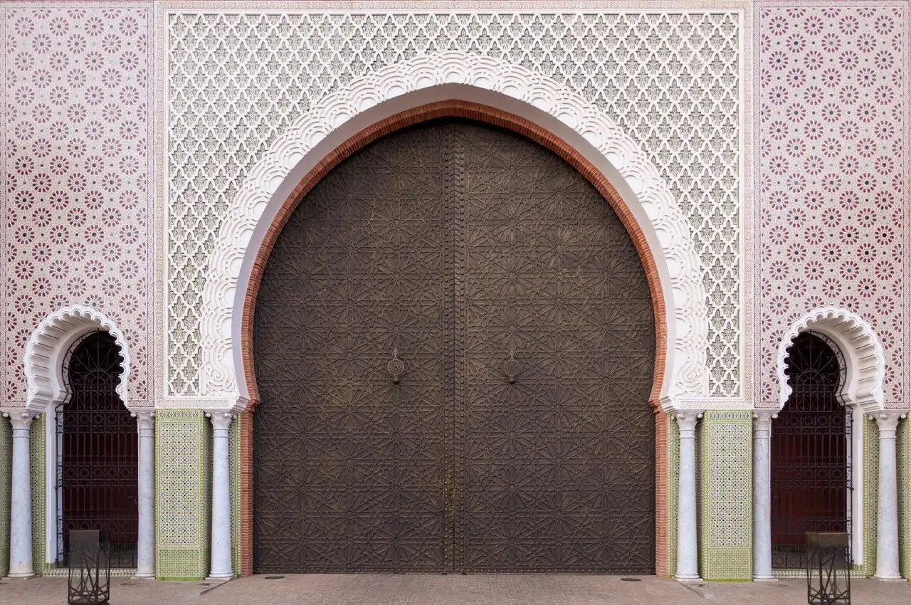 Portone marocchino ad arco con porte intagliate e piastrelle zellige su un itinerario di 14 giorni a Marrakech