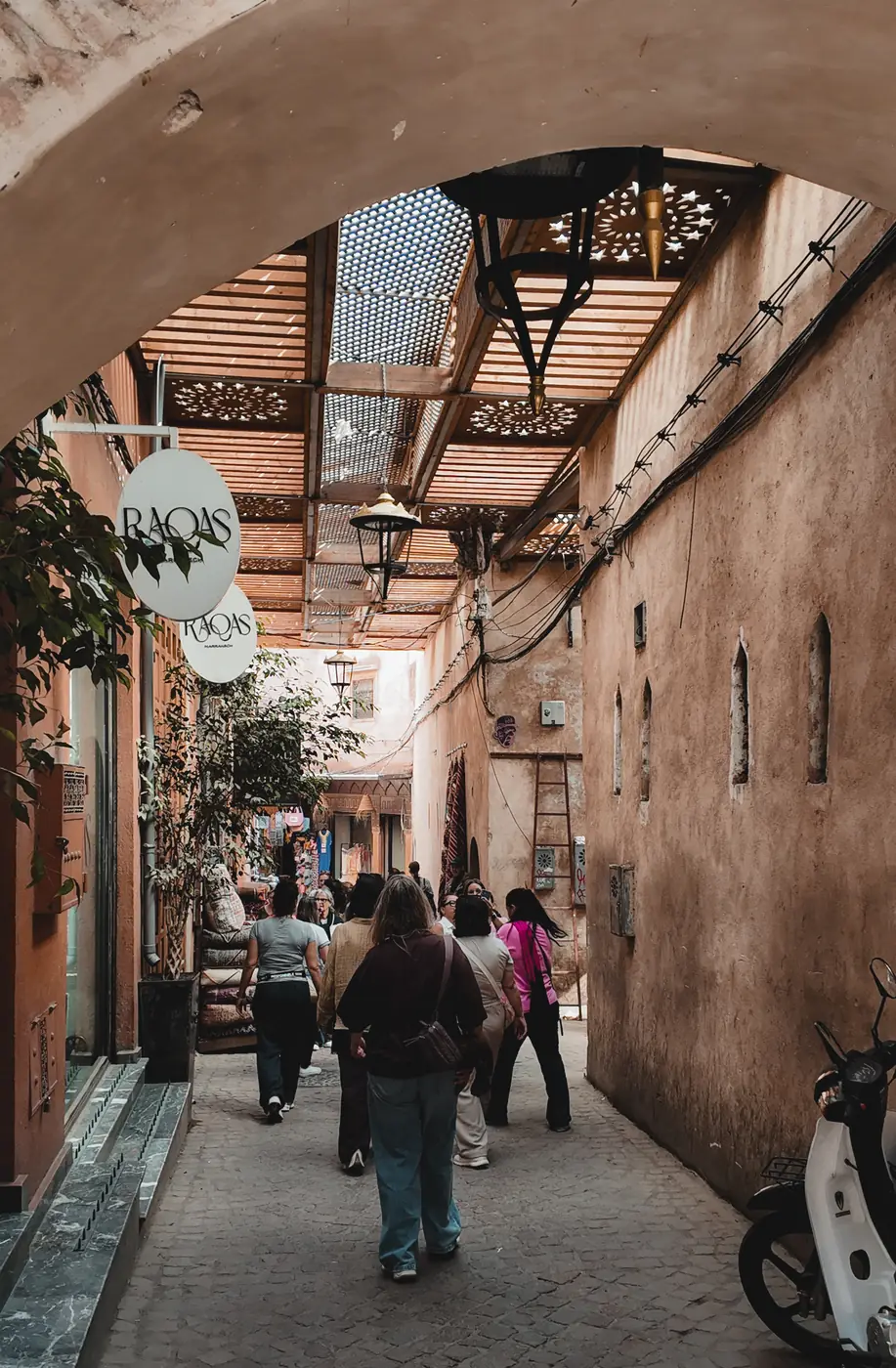 People walking through a covered souk alley in Marrakech medina