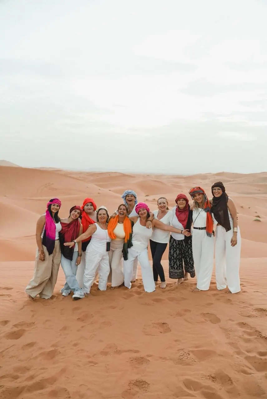 Travelers wearing colorful headscarves posing together on the Erg Chebbi dunes